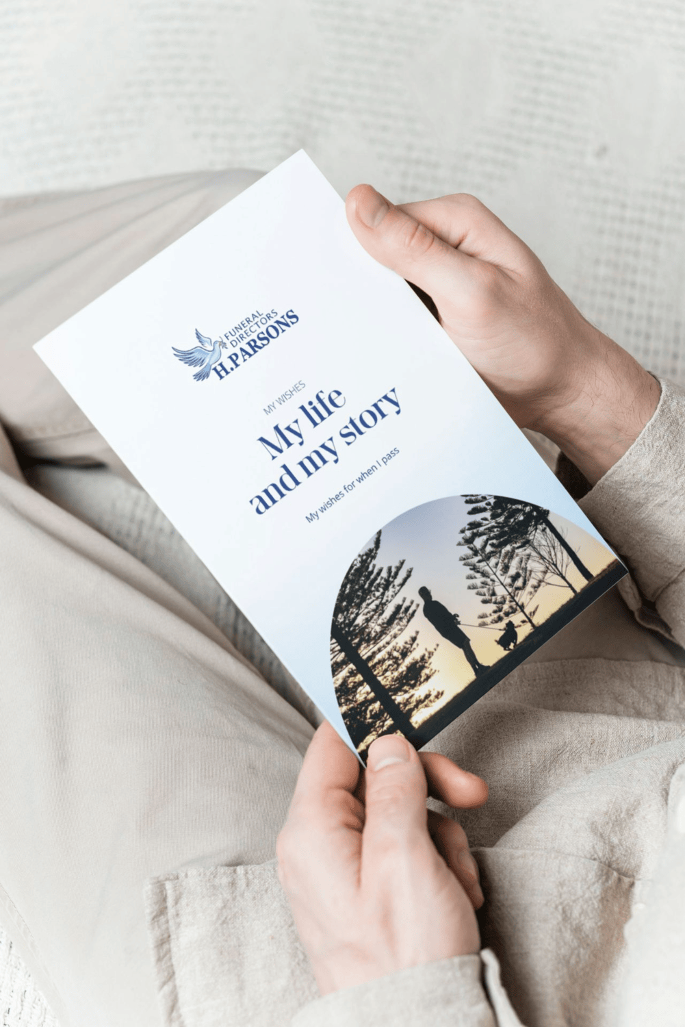 A person holds a My Wishes Booklet titled "My life and my story," featuring a silhouette of a person and dog among trees. This downloadable wishes booklet is provided by W. J. Parsons funeral directors. by H Parsons Funeral Directors